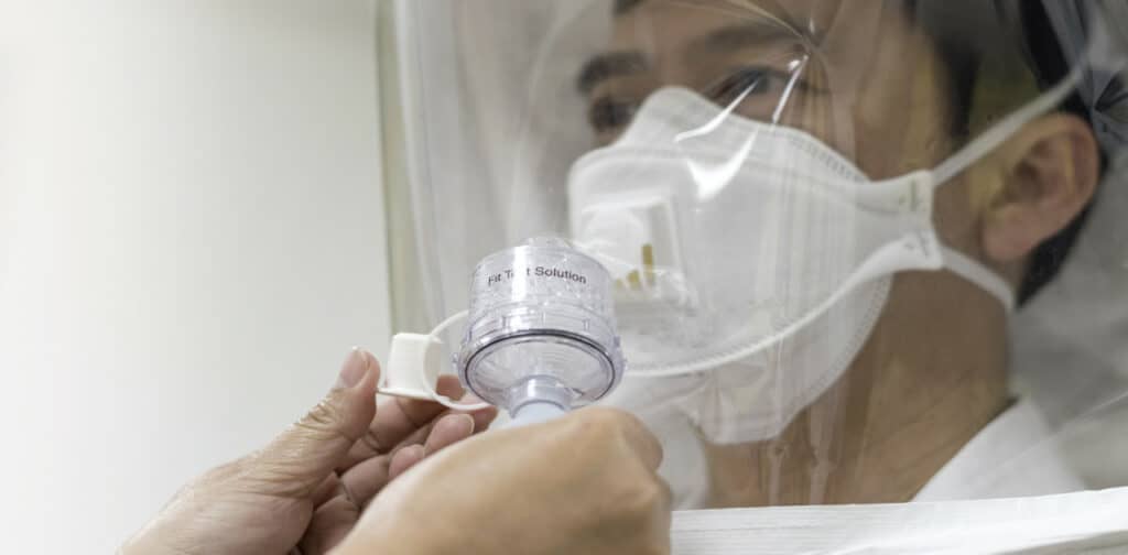 Asian man in a fit testing process with hood and fit test solution