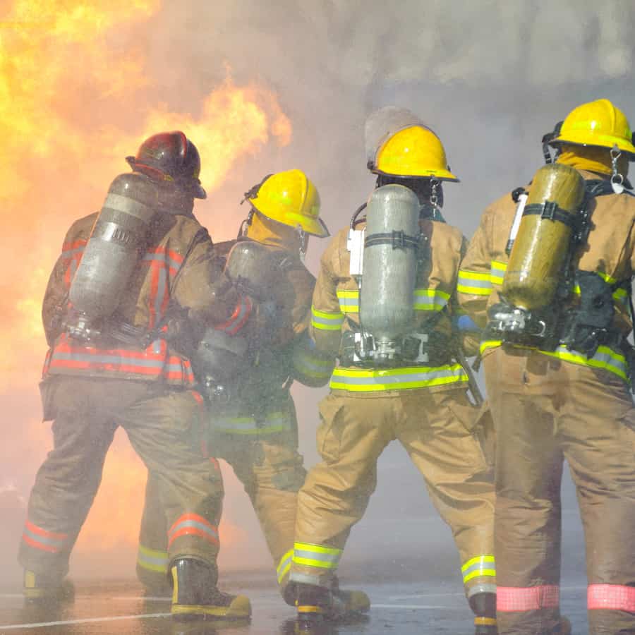 Directed by an officer in a red helmet, firefighters attack a propane fire during a training exercise.