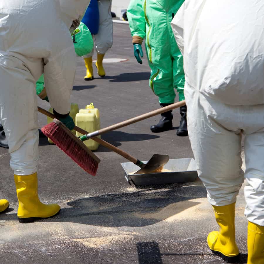 Men in protective gear cleaning up after chemical accident.