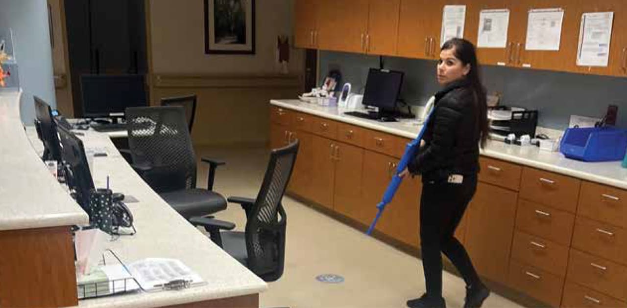 A woman behind a desk in a hospital walks with a mock wooden rifle during a simulated active threat exercise.