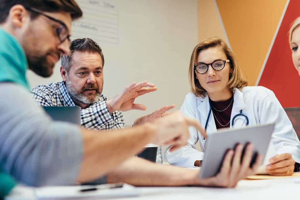 Team of doctors and others looking at a tablet