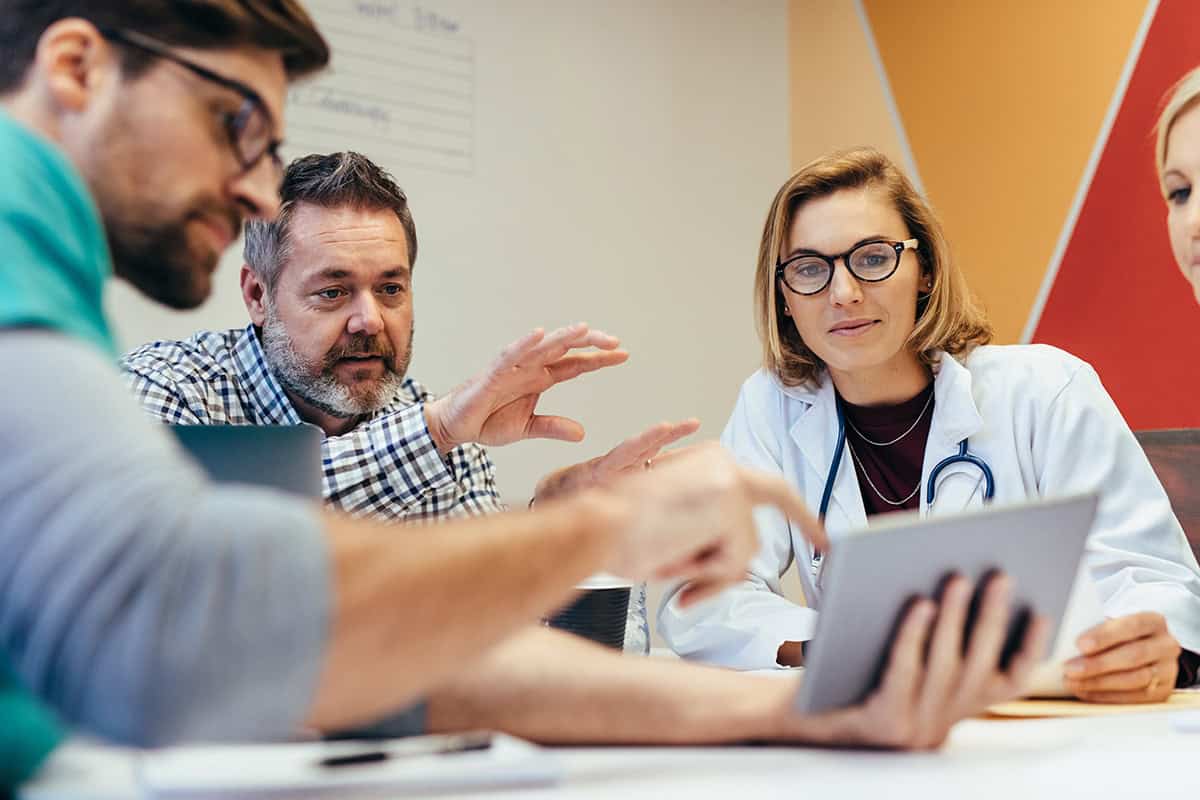 Team of doctors and others looking at a tablet